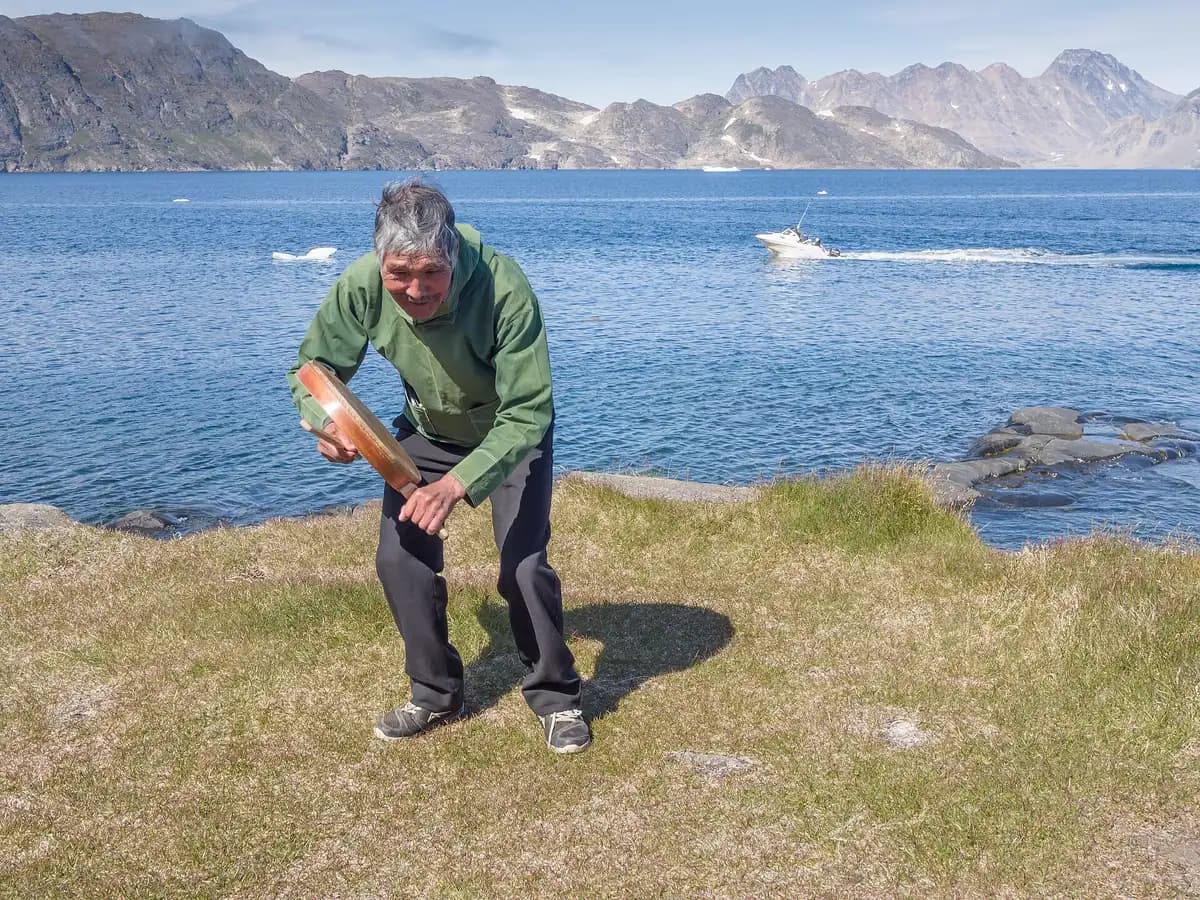 Greenland: a drum dancer performing beside a fjord in east Greenland